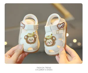 Detailed view of white toddler sandals featuring cute cartoon embroidery and closed-toe design.