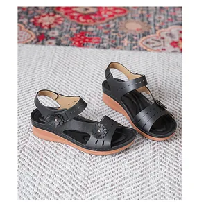 Detailed side view of women's black platform sandals with decorative flowers on a textured rug