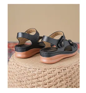 Rear view detail of black wedge sandals with decorative floral accent and thick sole.