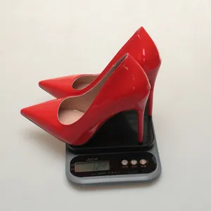 Red pointed-toe stiletto pumps being weighed on a scale showing lightweight design