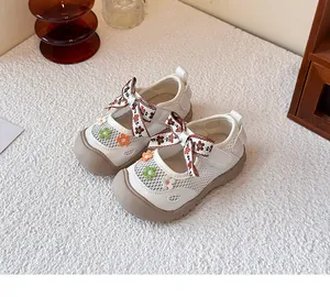 Primer plano de zapatos de malla blancos para niña con bordados florales y lazo