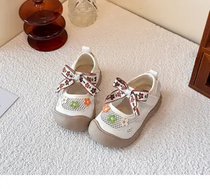 Detalle de zapatos Mary Jane de malla para niños con lazo floral y bordado.