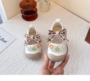 Detalle de zapatos infantiles de malla blanca transpirable con bordado de flores y lazo