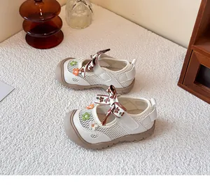Detalle de los zapatos de malla para bebé con flores bordadas y lazo decorativo