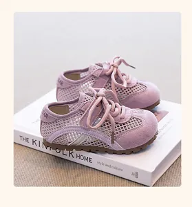 Close-up of girls' breathable purple mesh sneakers on a minimalist book background.