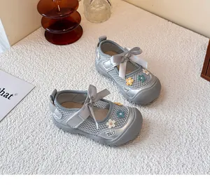 Detalle de zapatos infantiles de malla plateada con lazos elegantes y bordado floral