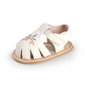Close-up of baby girl's white walker sandals with elegant pink flower embroidery