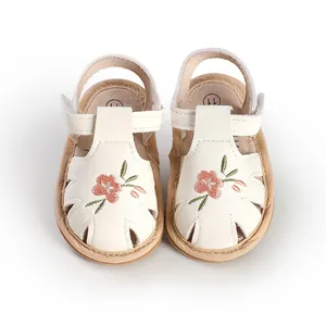 Close-up of white baby girl sandals with delicate floral embroidery and soft soles