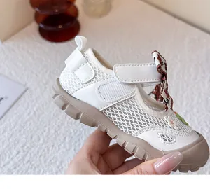 Primer plano de zapatos de malla blanca para bebé con detalles de flores y lazo