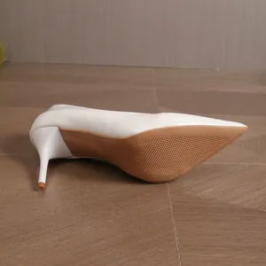 Detail view of white pointed high heel pump showing tan non-slip sole and stiletto.