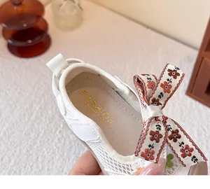 Detalle de zapatos de malla blanca para bebé con lazo floral decorativo