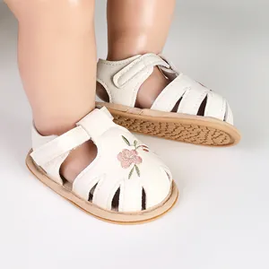 Detailed view of white baby girl sandals featuring delicate floral embroidery and soft soles