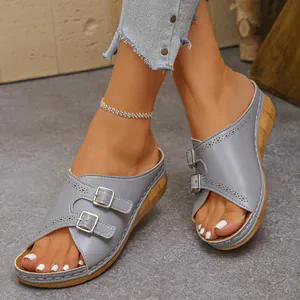Detailed view of grey wedge sandals with adjustable double buckles and open toe design