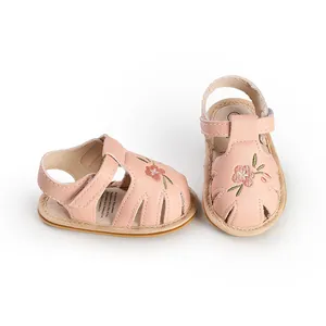 Macro view of pink baby girl sandals featuring delicate floral embroidery and soft soles.