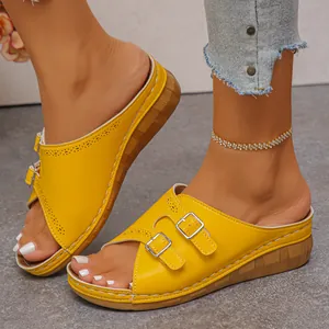 Close-up of yellow wedge sandals with double buckle detail and peep toe design