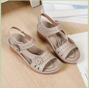 Detail of wedge sandals with floral accents and laser-cut patterns on soft beige leather.