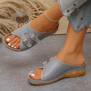 Detailed close-up of grey wedge sandals with dual buckles and perforated accents