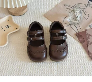 Close-up of brown girls' Mary Jane shoes with double straps and wingtip details