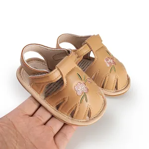 Detailed view of tan baby girl sandals with pink flower embroidery and velcro strap