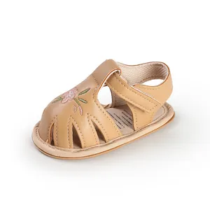 Close-up of beige baby girl sandal with delicate pink flower embroidery detail.