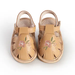 Detailed top view of beige toddler walking sandals with delicate pink flower embroidery