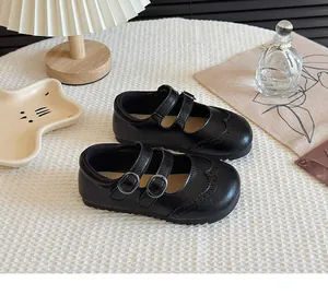 Detail view of black Mary Jane shoes for girls with elegant brogue patterns.