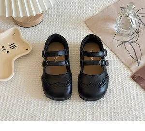 Macro view of black girls' Mary Jane shoes with double buckle straps and brogue detail