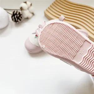 Close-up detail of the non-slip wavy textured rubber sole on pink baby walking shoes.