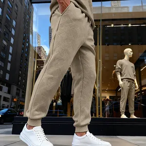 Detalle de los pantalones de chándal beige para hombre con textura de patrón geométrico.