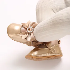 Close-up detail of champagne gold baby shoes with elegant bow and rhinestone buckle decoration