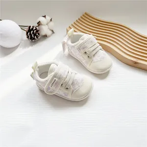 Detailed view of floral baby walking shoes with hook-and-loop straps on a wooden board