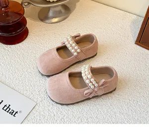 Close-up of pink suede girl's Mary Jane shoes with elegant pearl straps and bow details.