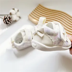 Detailed view of floral baby girl walking shoes featuring a white bow and Velcro strap