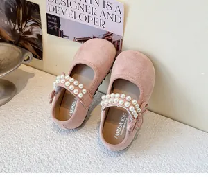 Close-up of pink suede girls princess shoes with elegant pearl straps and bow.