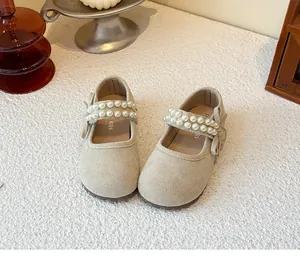 Close-up detail of beige suede girls' Mary Janes featuring double pearl straps and bows.