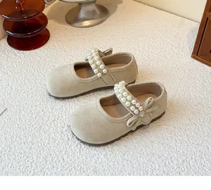 Close-up of beige toddler girl's Mary Jane flats featuring pearl straps and bow details.