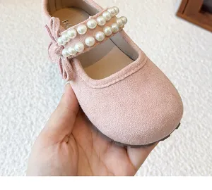 Close-up of pink suede girl's Mary Jane shoes with elegant double pearl straps and bow