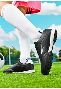 Action shot of black TF turf soccer shoes on green grass field