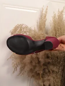 Detailed view of the black anti-slip sole and block heel on burgundy suede sandals