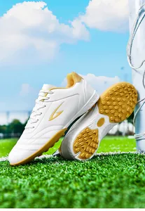 White and yellow TF turf soccer shoes with short studs on a green grass field
