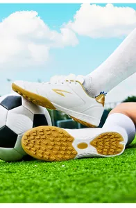 Detail of white soccer turf shoes showing sole and side profile on grass field