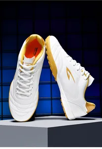Close-up of white breathable TF turf soccer shoes with golden accents and deerway logo.