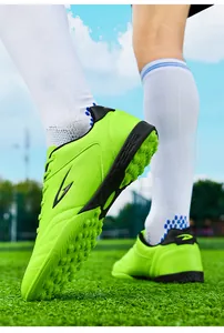 Detail showing neon green breathable football shoes with TF studs on a sports field