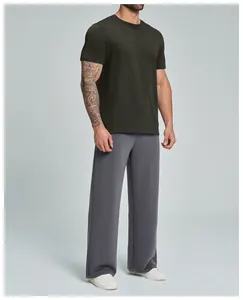 Hombre con camiseta de algodón orgánico verde oliva oscuro y pantalón de chándal gris
