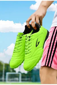 Close-up of vibrant neon green turf soccer shoes for training on outdoor field background