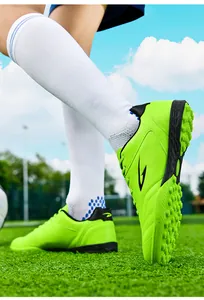 Detailed view of lime green TF soccer shoes with rubber studs on a grass field