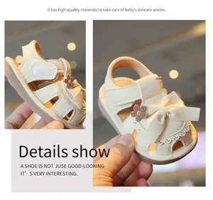 Detailansicht der cremefarbenen Baby-Sandalen mit Schleife und feinem Blumendekor