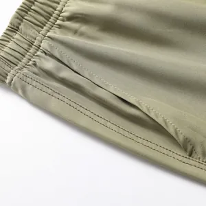 Detail of men's olive green quick-dry sports shorts with elastic waist and side pocket.