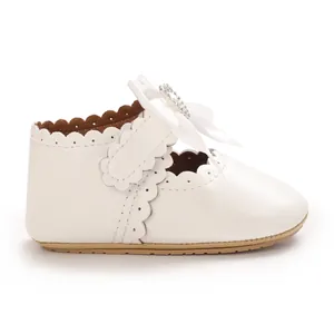 Detailansicht weißer Baby-Prinzessin-Schuh mit seidiger Schleife und Strassstein-Dekoration