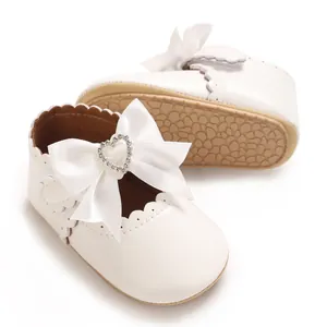 Detailansicht der weißen Baby-Prinzessinenschuhe mit Schleife und Herz-Strass-Detail